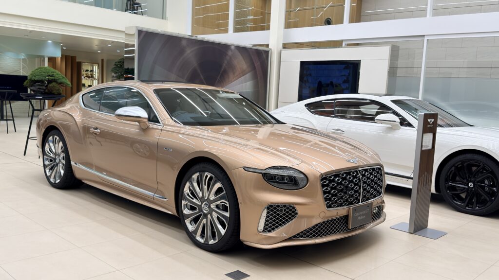 白いレンガ壁のエントランスに飾られた黒松の盆栽とBENTLEYロゴのカウンター|盆栽レンタル